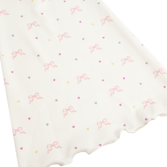 Close-up detail of the Bow Print Bolero Top showcasing the ivory fabric printed with delicate pink ribbon bows and pastel heart motifs, highlighting the soft romantic Lana Del Rey-inspired pattern.