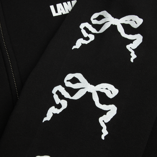 Close-up detail of the Ribbon Sleeve Black Zip-Up Hoodie showcasing the repeating white ribbon bow graphics printed along the black sleeve, highlighting the minimalist Lana Del Rey-inspired vintage aesthetic.