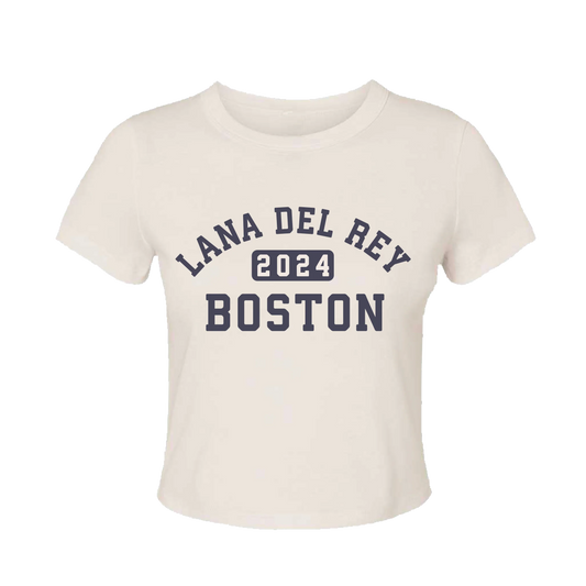 Front view of the Boston Baby Tee by Lana Del Rey featuring a cream fitted baby tee with Lana Del Rey 2024 Boston varsity-style graphic, inspired by the 2024 Fenway Park concert collection and exclusive tour merchandise.