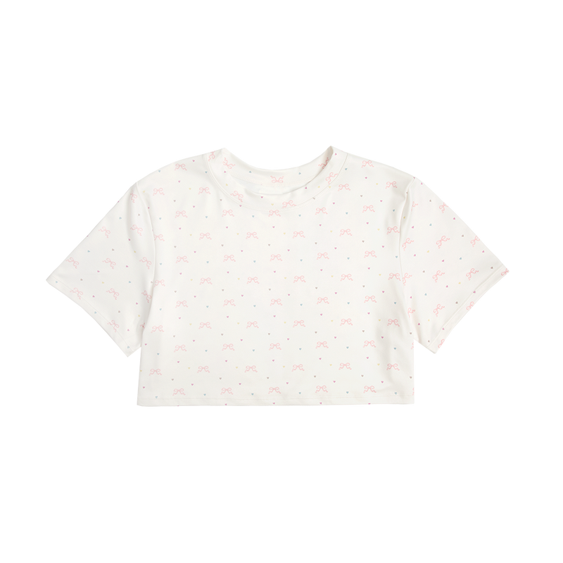 Front view of the Bow Print Cropped T-Shirt featuring an ivory cropped tee with an all-over pink ribbon bow and pastel heart print, designed with a soft romantic aesthetic inspired by Lana Del Rey.