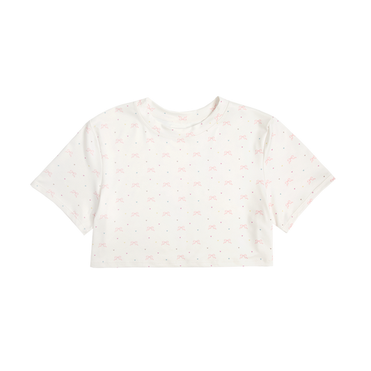 Front view of the Bow Print Cropped T-Shirt featuring an ivory cropped tee with an all-over pink ribbon bow and pastel heart print, designed with a soft romantic aesthetic inspired by Lana Del Rey.