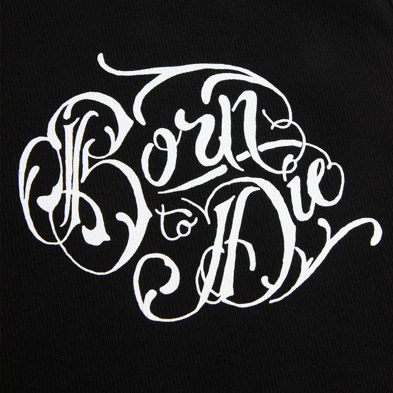 Close-up detail of the Lana Del Rey Black Ribbed Print Tank Top showcasing the ornate white Born to Die script artwork printed on black ribbed fabric inspired by Lana Del Rey's classic Born to Die album merch.