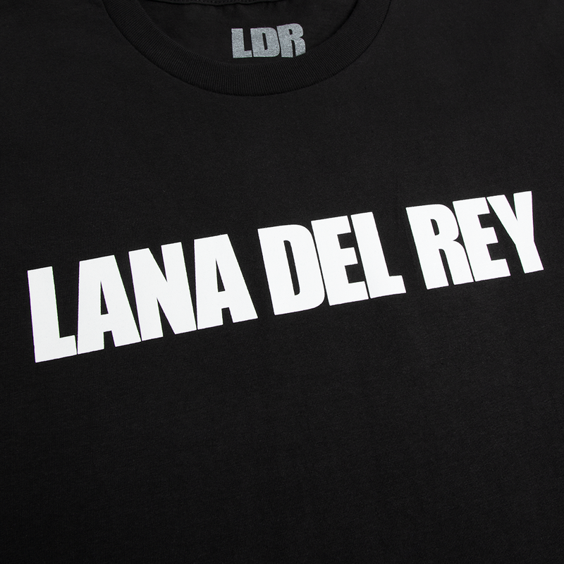 Close-up detail of the Lana Del Rey Logo Black T-Shirt showcasing the bold white Lana Del Rey wordmark printed on black cotton fabric, highlighting the minimalist graphic and premium screen print finish.