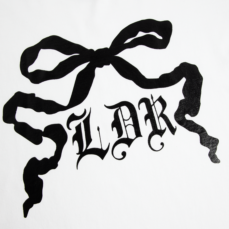 Close-up detail of the Ribbon Graphic White T-Shirt showcasing the black ribbon bow artwork with gothic LDR lettering printed on white cotton fabric, highlighting the vintage-inspired graphic design.