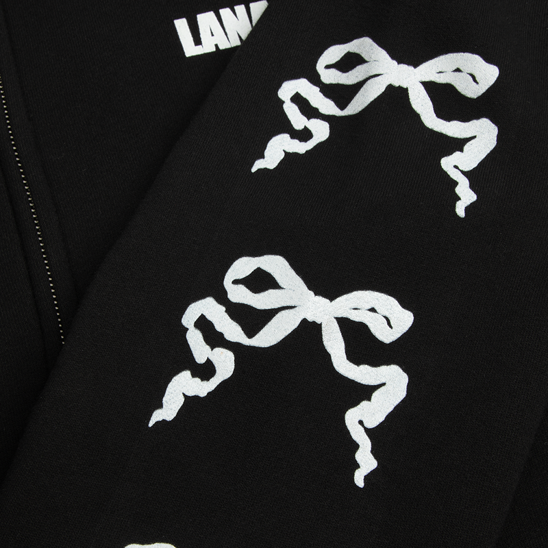 Close-up detail of the Ribbon Sleeve Black Zip-Up Hoodie showcasing the repeating white ribbon bow graphics printed along the black sleeve, highlighting the minimalist Lana Del Rey-inspired vintage aesthetic.